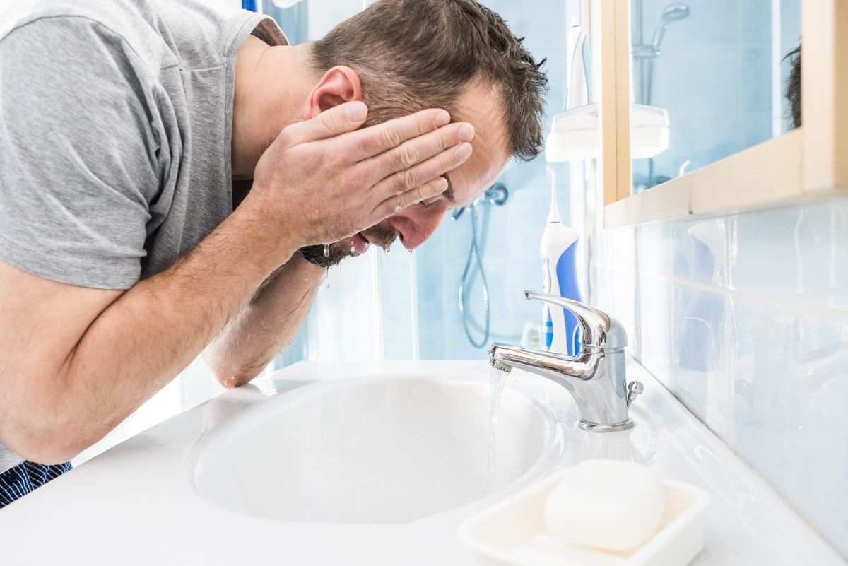 Man splashing water on his face, washing himself, taking care of personal hygiene. Feeling fresh in the morning