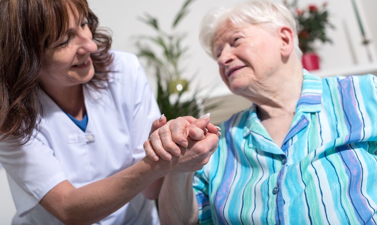 Nurse holding the hand of an old woman